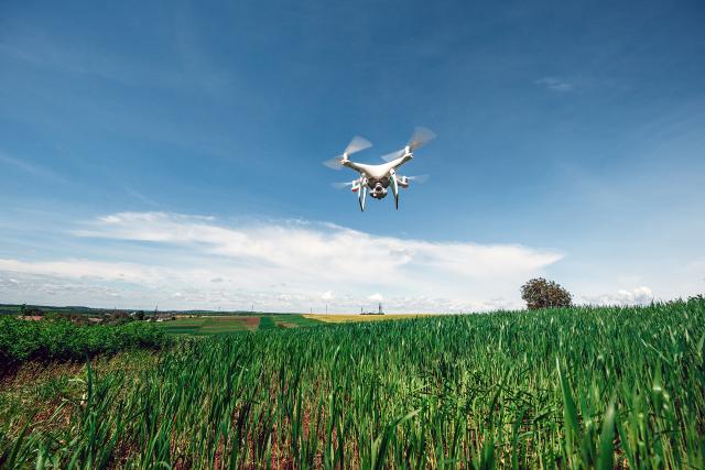Drone with camera flying over field of grass